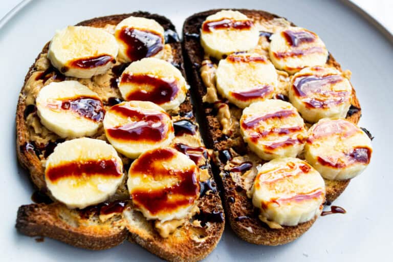 Buttered toast topped with sliced bananas, peanut butter, and drizzled with chocolate syrup, healthy breakfast, simple fresh food ideas, nutritious snack, delicious toast recipe.