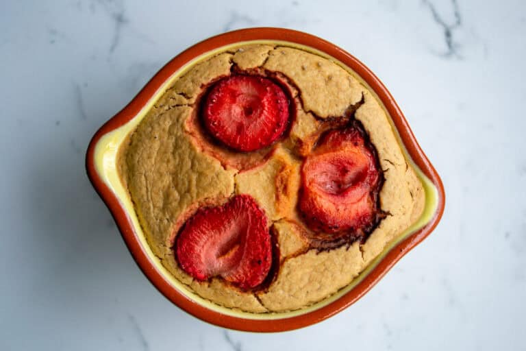 Fresh strawberry cobbler baked in a rustic oven-safe dish, topped with golden crust and juicy strawberries, perfect for summer desserts.