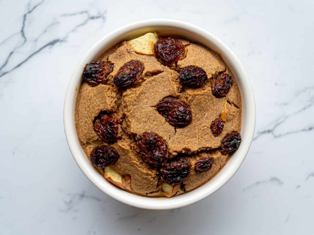 Apple baked oats in a ramekin with raisins on top.