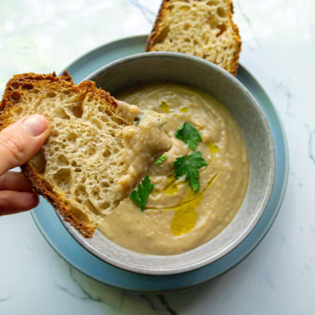 cauliflower and white bean soup in a bowl with sourdough bread