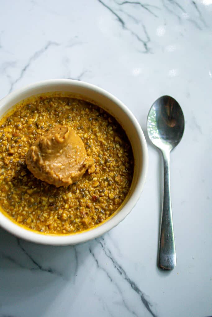 vegan pumpkin overnight oats in a bowl with peanut butter and spoon