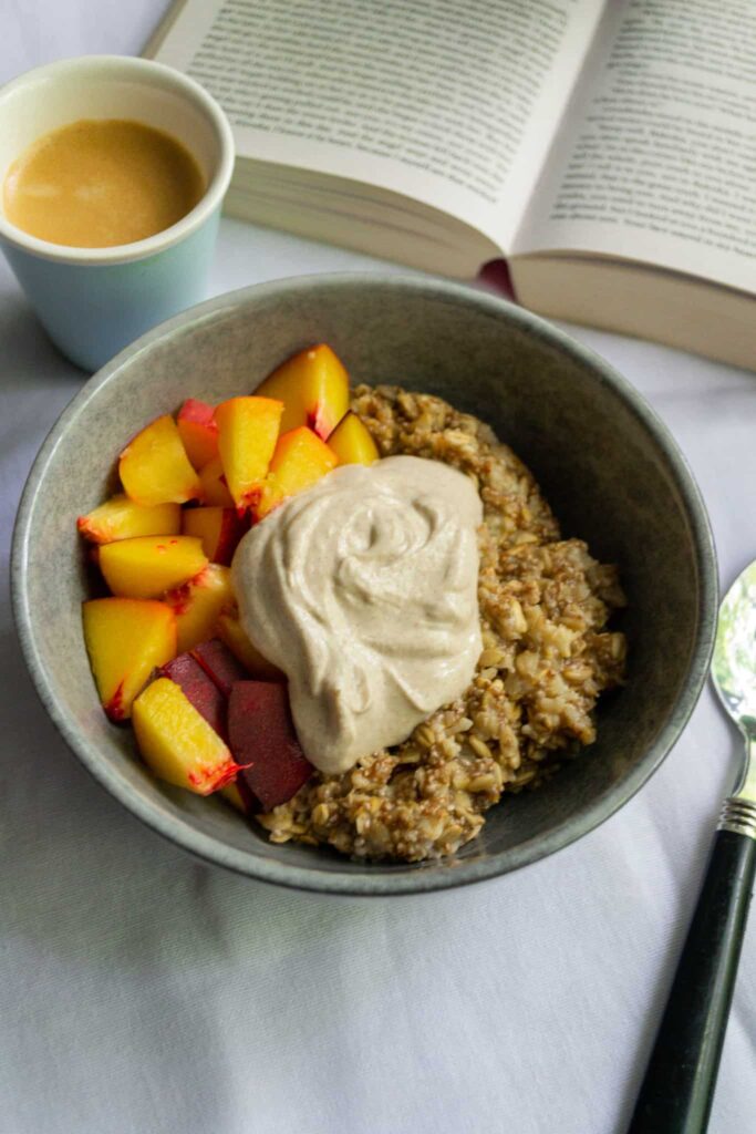 peach and cream oatmeal on a table with a book