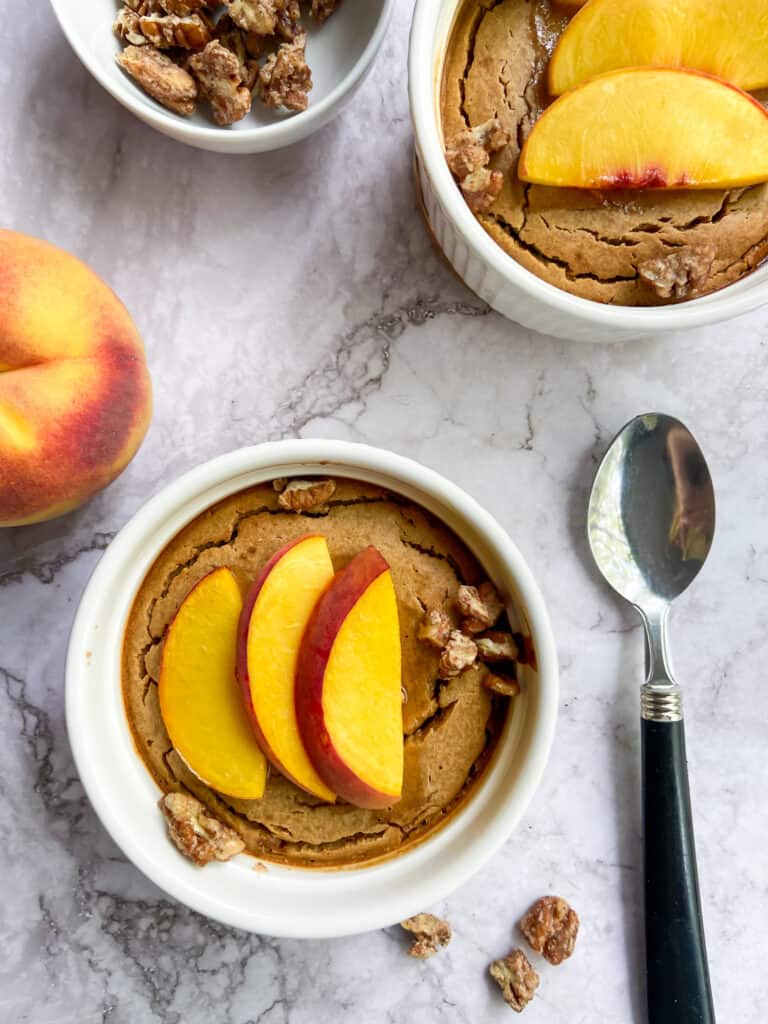 two bowls of peach baked oatmeal on a marble table