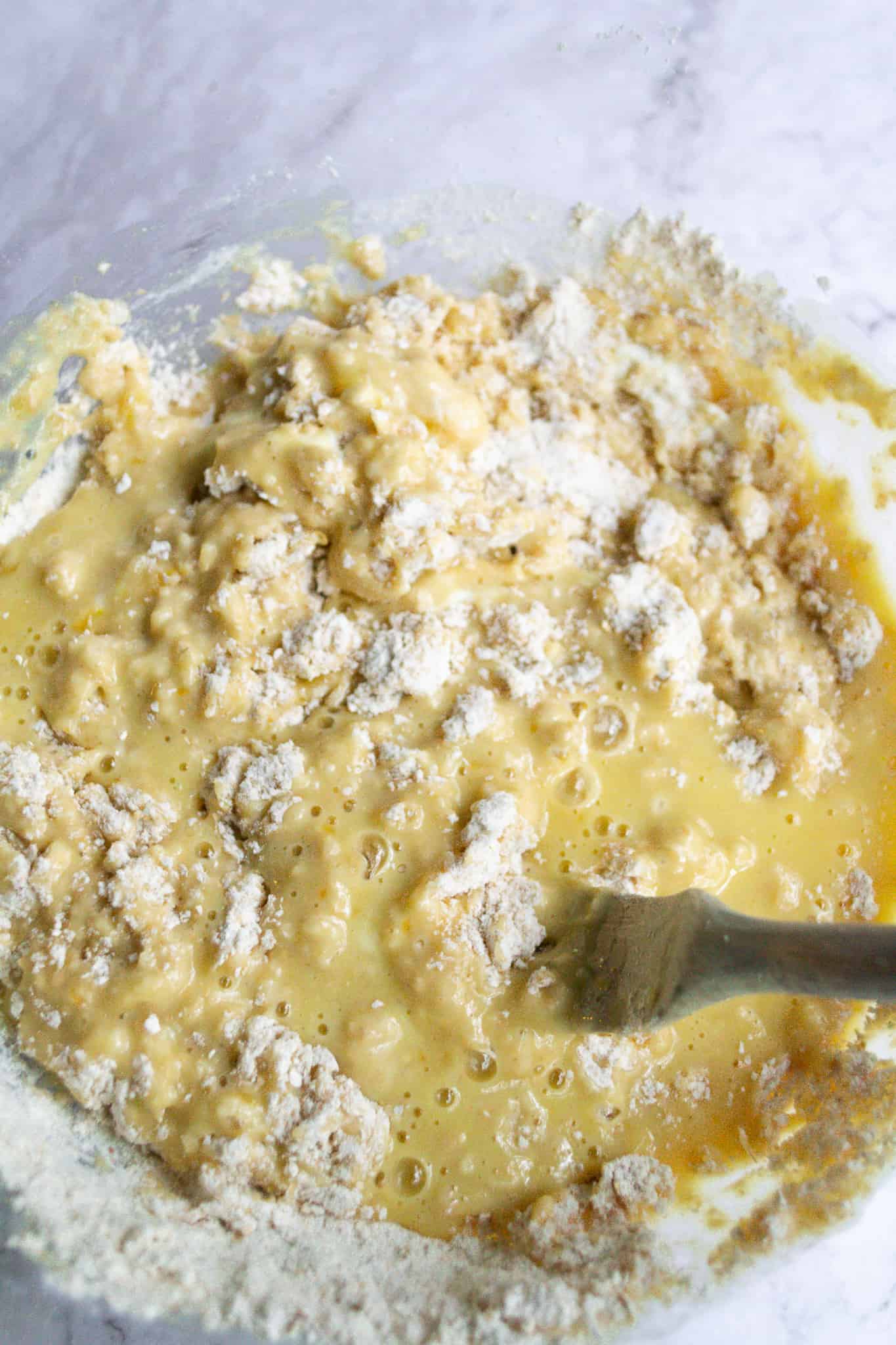 Dry and wet ingredients being mixed for bread in a bowl.
