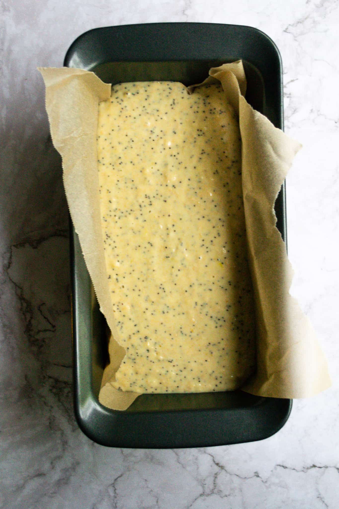 Orange poppyseed loaf batter in a pan with baking paper.