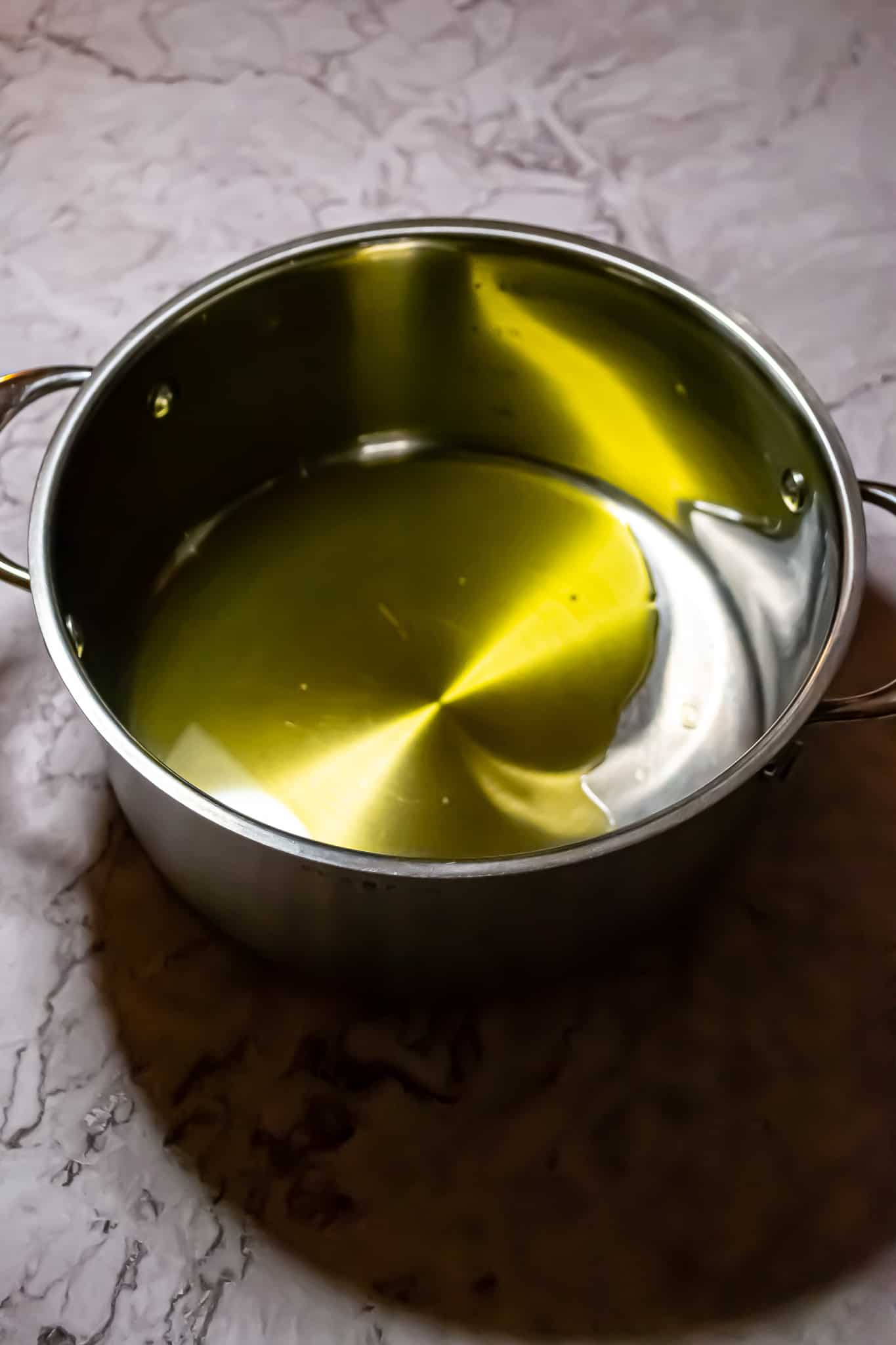 Top view of extra virgin olive oil in a stainless steel soup pot.