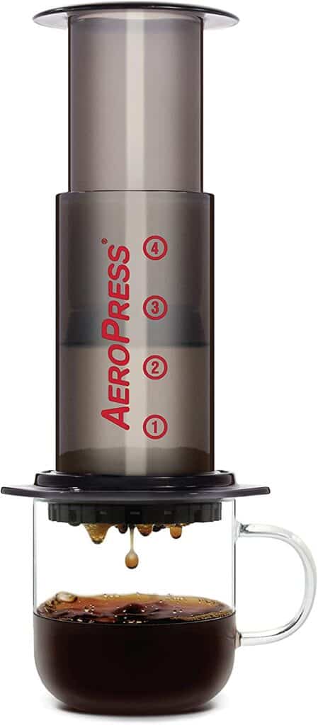 Product shot of AeroPress extracting coffee into a glass mug. 