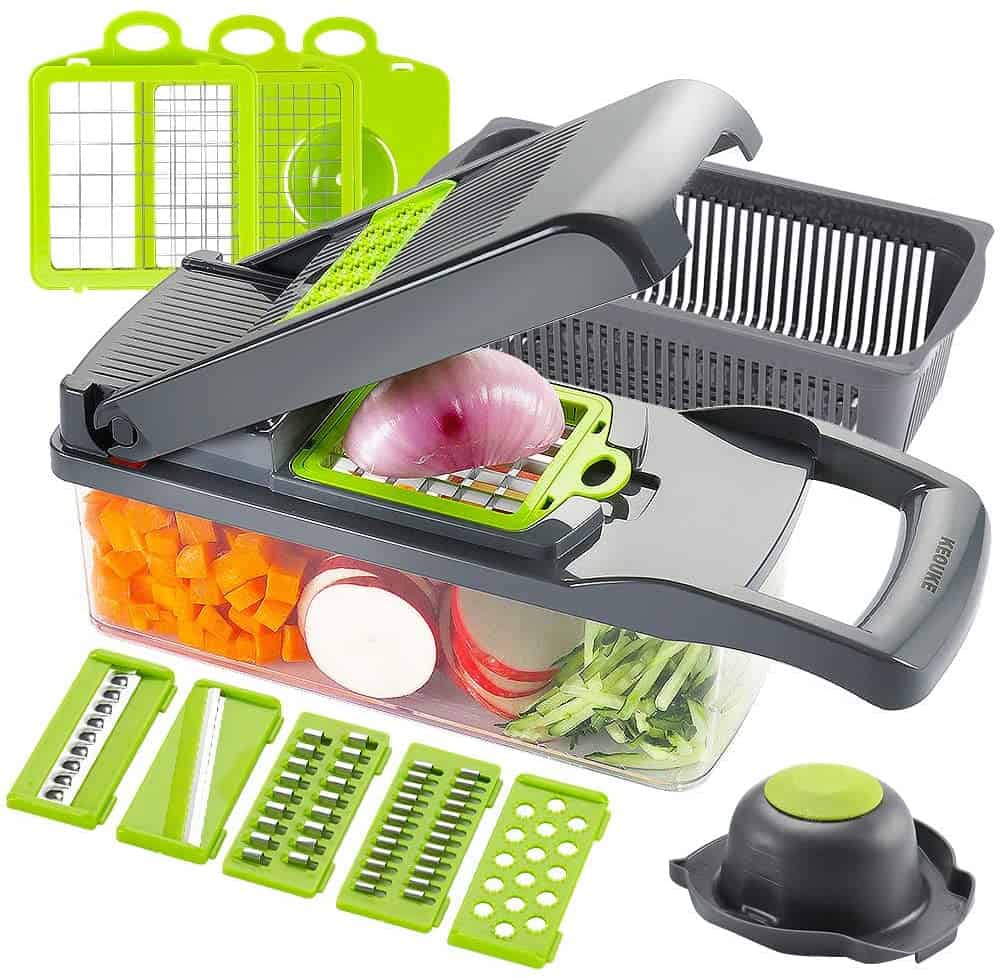 Product shot of the KEOUKE vegetable chopper. The  chopper is full of vegetables and there is an onion being diced. The background and foreground show different blade options. 