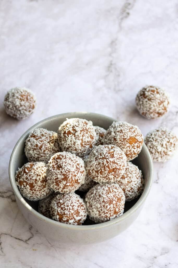 Top view of Tim Tam balls in a grey bowl on a marble table.