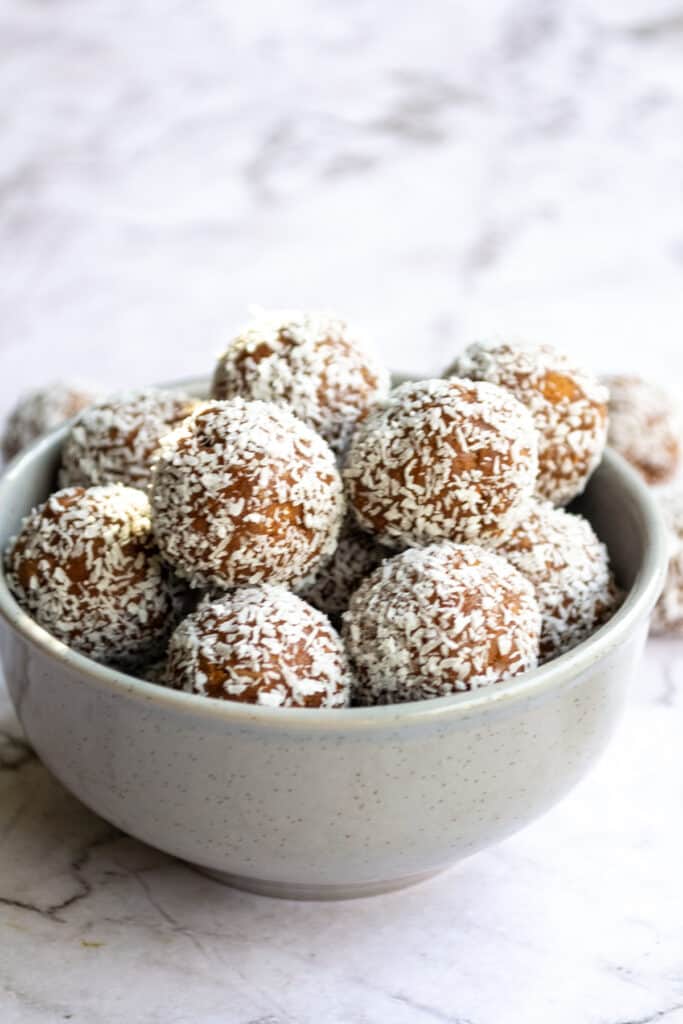 Side view of Tim Tam balls in a grey bowl on a marble table.