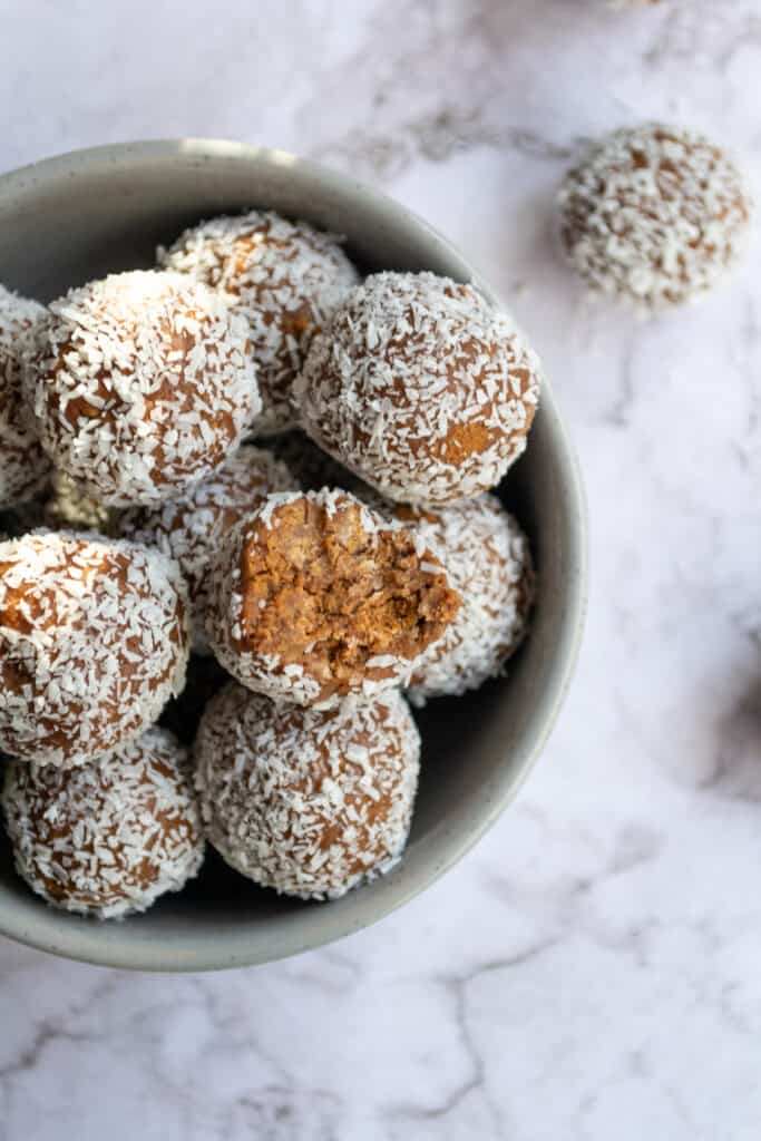 A bunch of Tim Tam balls in a grey bowl on a marble table.