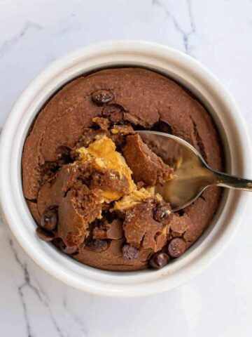 Chocolate peanut butter baked oats in a ramekin, with peanut butter melting in the centre.