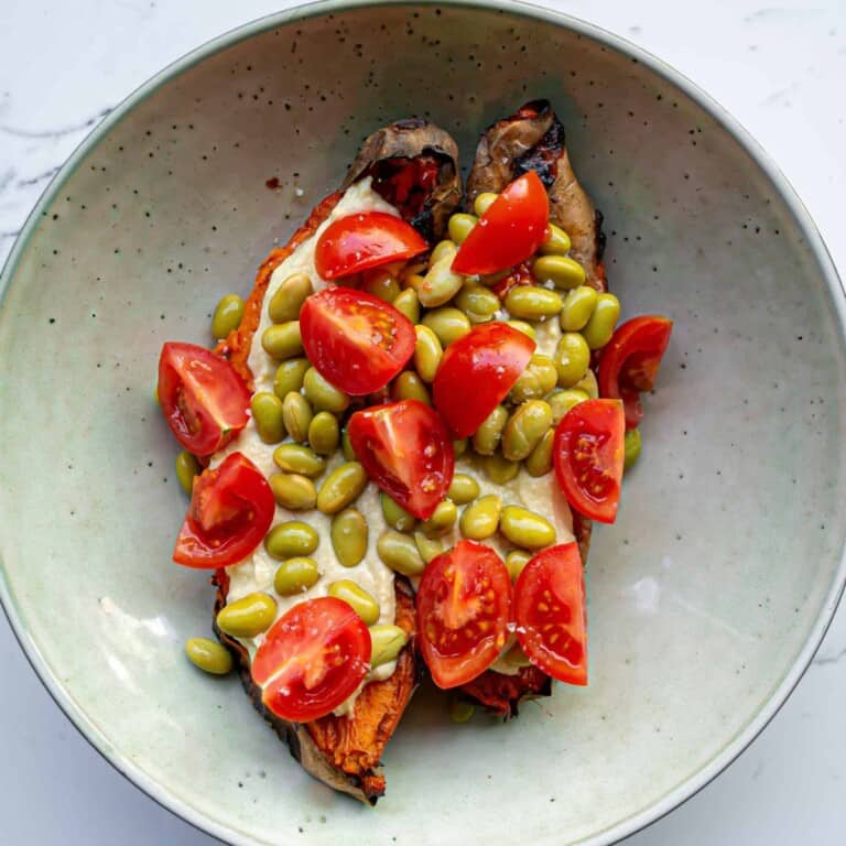 Roasted eggplant topped with cherry tomatoes, green beans, and fresh mozzarella cheese, served in a light green bowl. Perfect for healthy, delicious, and nutritious vegetarian meals and easy to prepare at home.