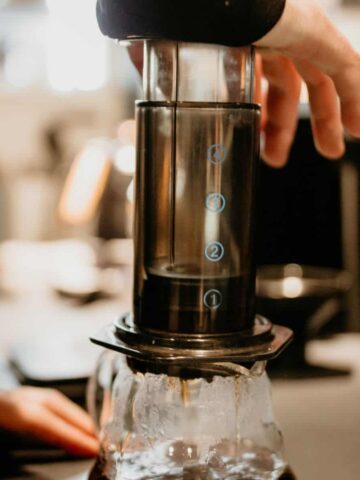 Person using an aeropress to extract coffee into a glass coffee jug.