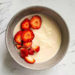 Soy yogurt in a bowl with strawberries on top.