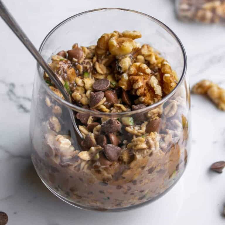 Crispy granola with chocolate chips in a clear glass on white marble surface, healthy homemade snack or breakfast, nutritious, fresh ingredients, simple recipe, cool food ideas, Simply Fresh Foodie.