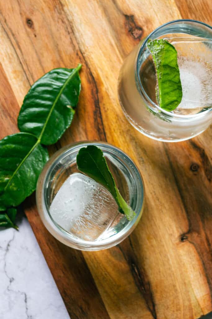 An overhead shot of two yuzu moctails in glasses sitting on a wooden board.