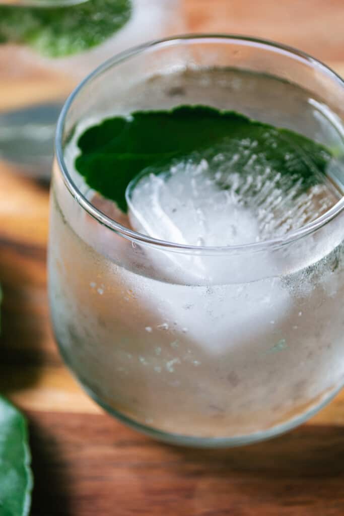 A close-up photo of a yuzu mocktail in a glass sitting on wood.