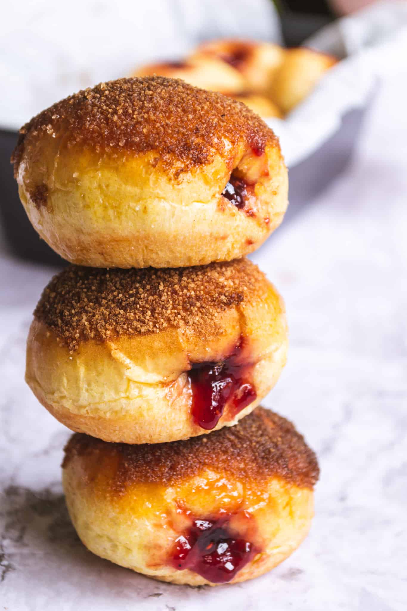 Three brioche donuts stacked on top of each other with jam coming out.