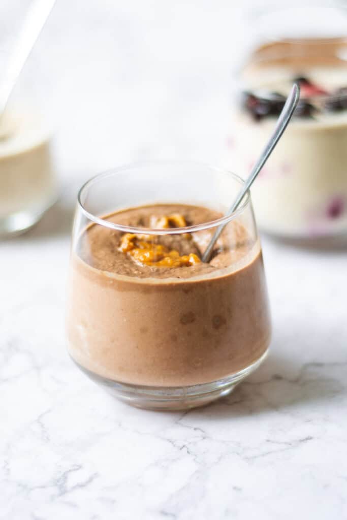 Individual photo of chocolate blended overnight oats in a cup with a spoon in it.