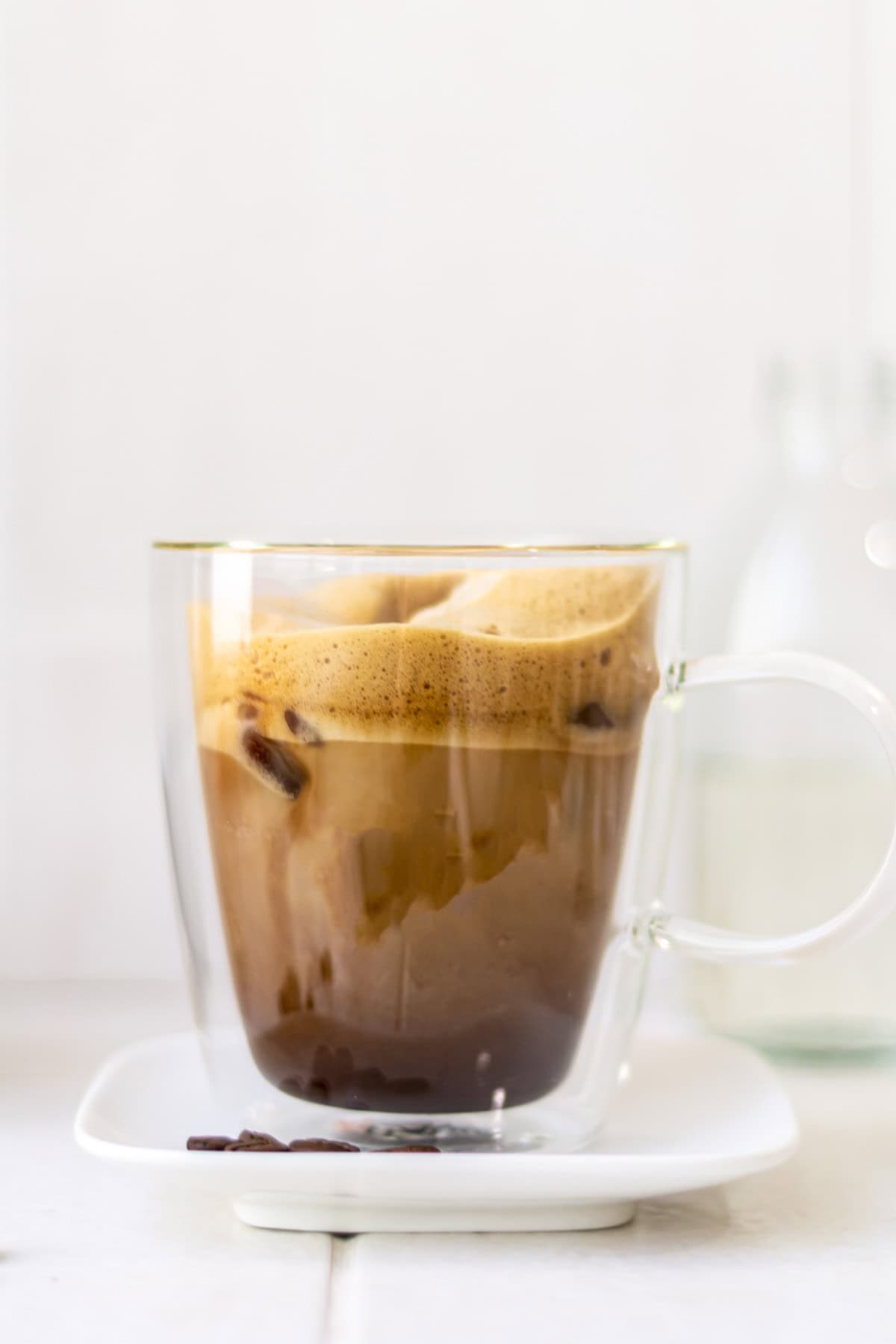 Iced shaken espresso with almond milk in a clear coffee mug.