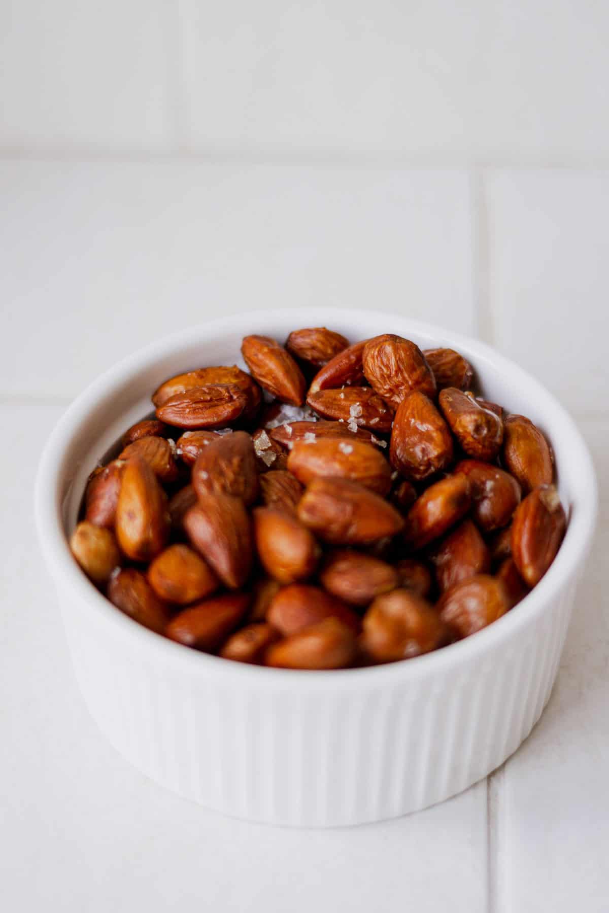 Roasted vinegar almonds in a bowl, sprinkled with flaky salt.