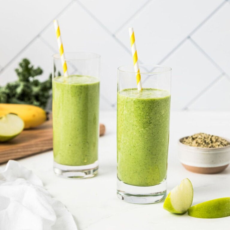 Refreshing green smoothie with fresh apples and leafy greens, served in tall glasses with yellow-striped straws, perfect for healthy eating and detox recipes.