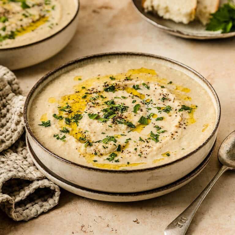 Creamy chicken and rice soup topped with fresh herbs, black pepper, and a drizzle of olive oil, served in a rustic bowl; perfect comfort food.