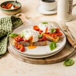 Soft poached eggs on tomato bruschetta with fresh basil on a white plate, served with coffee. Perfect for a nutritious breakfast or brunch featuring simple, fresh ingredients.