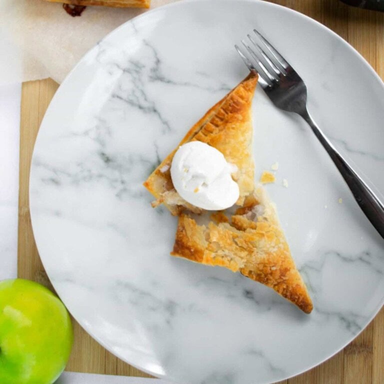 Buttermilk apple pie slice with whipped cream on marble plate, fresh apple nearby, simple dessert from simply fresh foodie, homemade apple pie, classic fall dessert, cozy baked good, easy apple pie recipe.