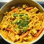 Savory vegan stir-fry with tofu, noodles, and vegetables in a flavorful sauce, garnished with chopped green onions, perfect for healthy dinner recipes.