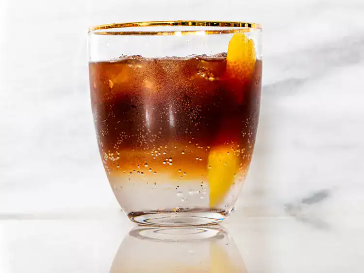 Espresso tonic in a clear glass with gold rim, as a non-alcoholic drink for New Year's.