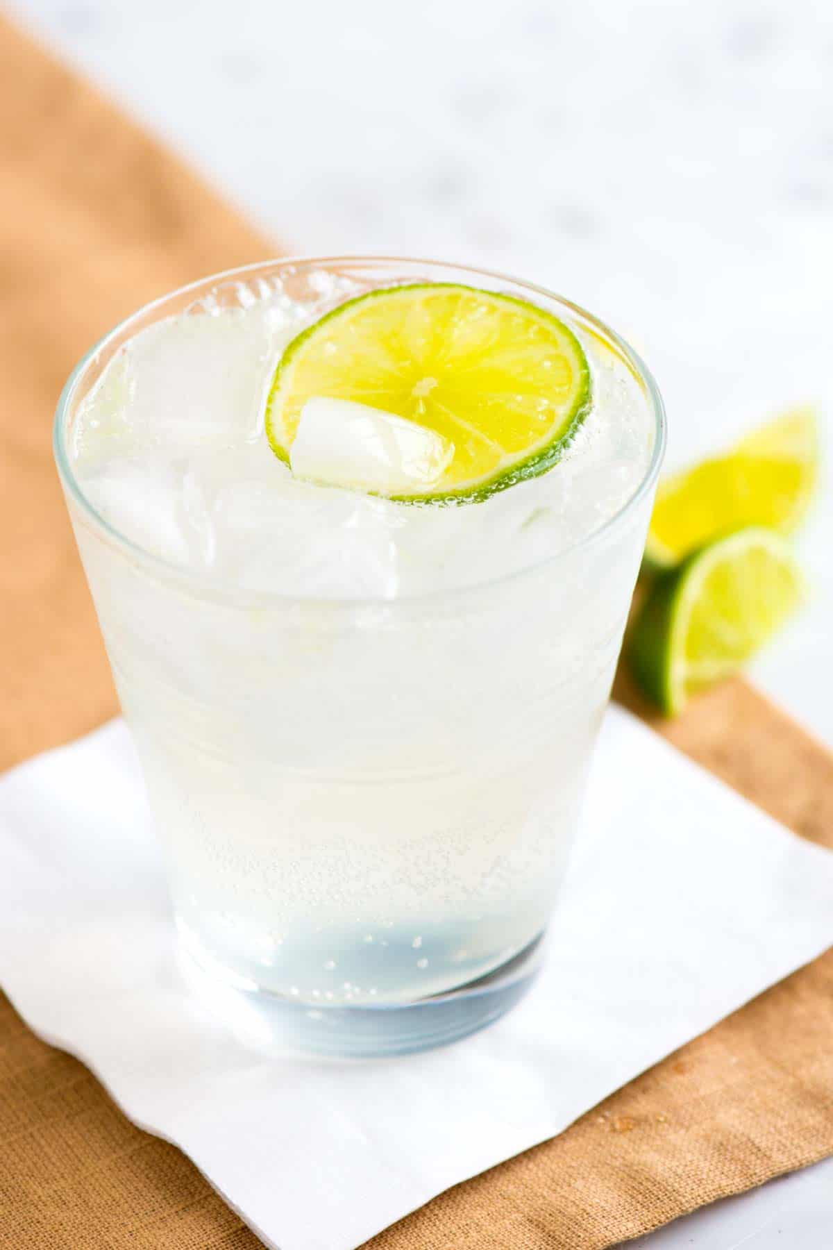 Gin and tonic served in a short glass with a lime slice.