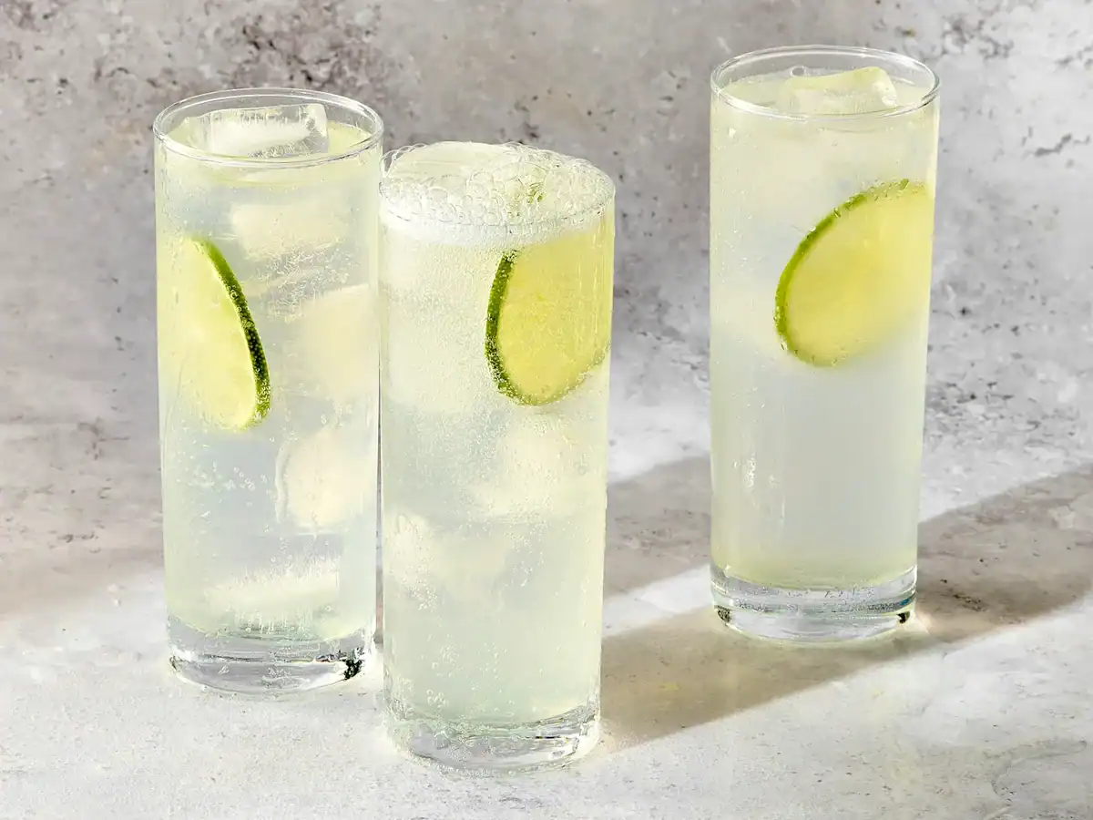 Gin Rickey cocktails served in highball glasses on ice with lime slices.